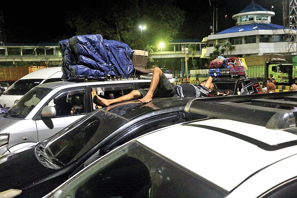 LELAH ANTRE: Pemudik tujuan Sumatera tertidur di atas mobil saat menunggu memasuki kapal ro-ro di Pelabuhan Merak, Banten, kemarin dini hari (5/5). (SALMAN TOYIBI/JAWA POS) - Image