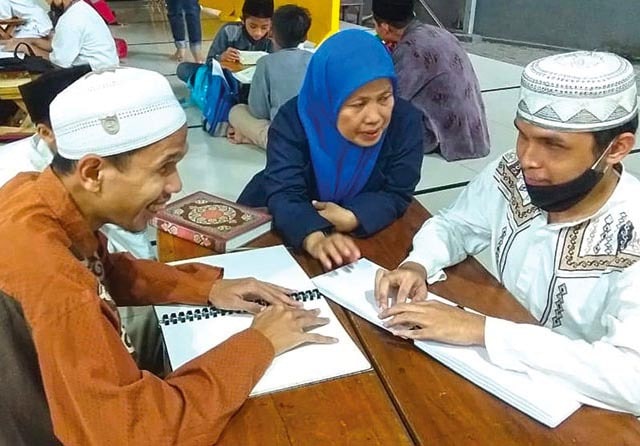 TELATEN: Umi Sa’adah sedang mengajar penyandang tunanetra mengaji dengan huruf braille. (Umi Sa’adah for Jaqa Pos) - Image