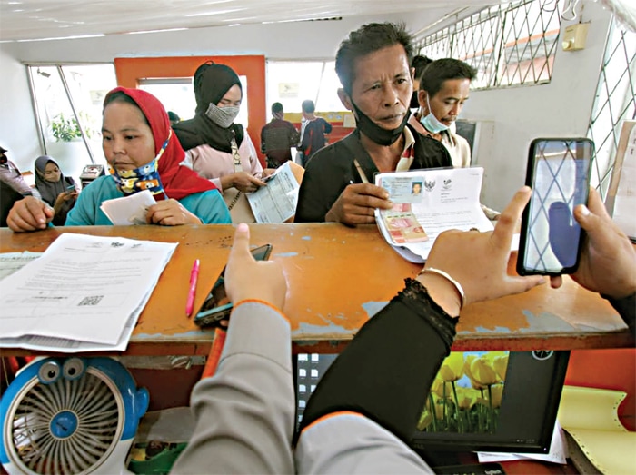 BANTUAN PEMERINTAH: Masyarakat menerima bansos tunai yang disalurkan melalui kantor pos. (SALMAN TOYIBI/JAWA POS) - Image