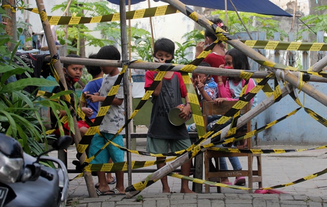Sejumlah anak-anak saat bermain di pagar pembatas isolasi di pemukiman warga RW 03, Kelurahan Gandasari, Kota Tangerang, Banten, Jumat (11/6/2021). RW 03 Kelurahan Gandasari Tangerang memberlakukan lockdown skala mikro setelah lebih dari puluhan warga t - Image