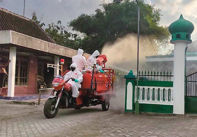 EMERGENCY: Petugas dari dinas kesehatan Lamongan melakukan penyemprotan disinfektan di Desa Sidodowo. (Jawa Pos Radar Lamongan) - Image