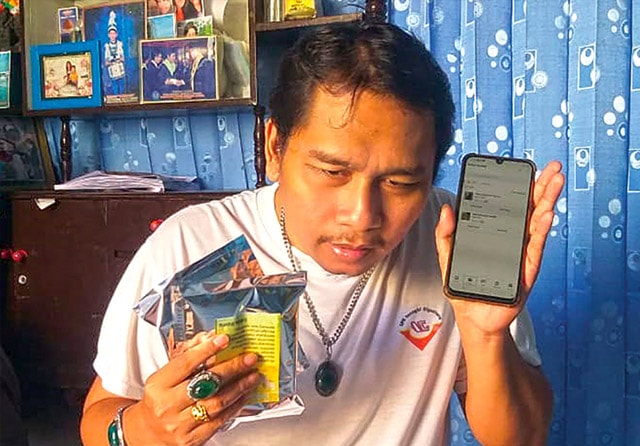 HARUS PELAN-PELAN: Danny Heru mendengarkan voice assistant untuk mengecek pertanyaan pelanhggan yang hendak membeli di tokonya. (Wahyu Zanuar Bustomi/Jawa Pos) - Image