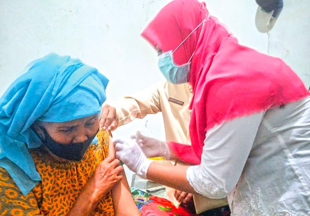 KAYAK DIGIGIT SEMUT: Nenek Yasni menjalani vaksinasi Covid-19. Dia mau menerima suntikan vaksin setelah dirayu oleh dokter dan lurah. (Shabrina Paramacitra/Jawa Pos) - Image