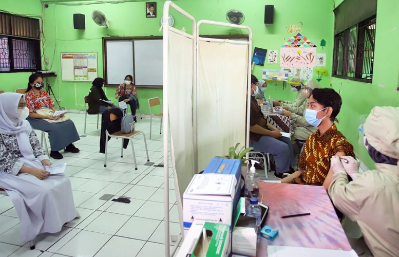 Sejumlah siswa mengikuti vaksinasi di SMAN 20 Jakarta, Kamis (01/07/2021). Kementerian Kesehatan RI mengeluarkan edaran tentang pelaksanaan vaksinasi COVID-19 bagi anak usia 12-17 tahun. Karena belum punya KTP, maka disyaratkan membawa kartu keluarga atau - Image