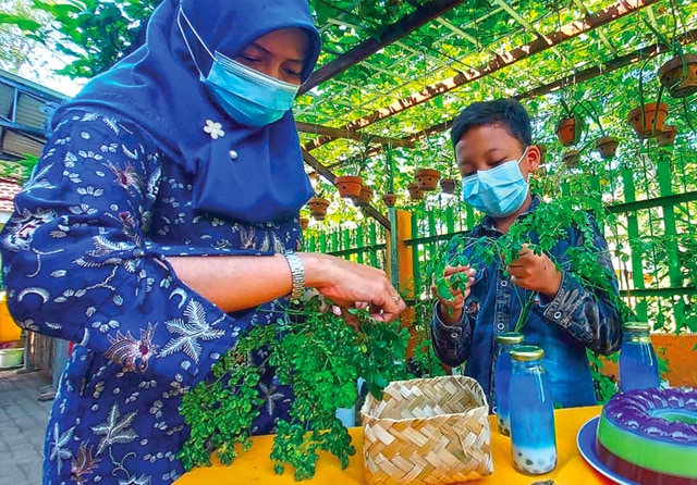 PEJUANG CILIK: Khrisnayana memamerkan beragam manfaat daun kelor. Tanaman itu bisa untuk pewarna hingga minuman. (Galih Adi Prasetyo/Jawa Pos) - Image