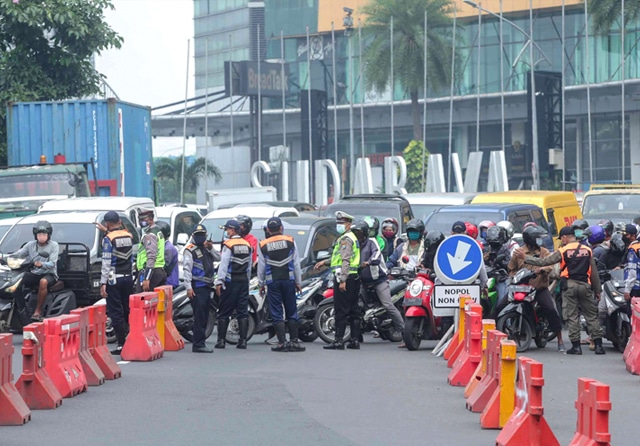 SYARAT KETAT: Tim gabungan dari kepolisian, dishub, dan satpo PP menghalau ratusan pengendara yang tak mampu menunjukkan dokumen sebagai syarat masuk ke Surabaya di bundaran Waru, Sabtu (3/7). (Alfian Rizal/Jawa Pos) - Image