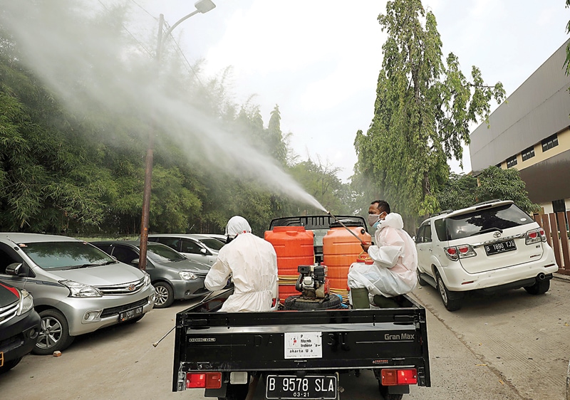 MUSNAHKAN VIRUS: Truk gunner spraying PMI menyemprotkan cairan disinfektan di Jalan Yos Sudarso, Jakarta Utara, kemarin. (FEDRIK TARIGAN/JAWA POS) - Image