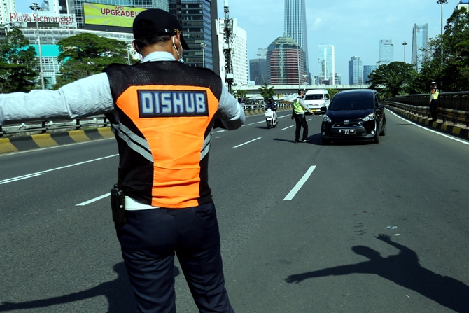 Petugas kepolisian melarang pengendara mobil berplat nomor ganjil memasuki Jalan Jenderal Gatot Subroto, Jakarta, Kamis (12/8/2021). Pemprov DKI Jakarta kembali menerapan sistem ganjil genap di delapan ruas jalan di Jakarta pada pukul 06.00-20.00 WIB untu - Image