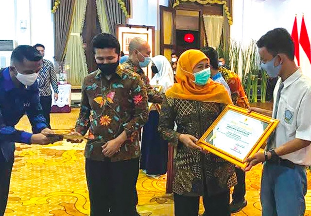 BERPRESTASI: Widianto Wahyu Utama saat menerima penghargaan dari Gubernur Jatim Khofifah Indar Parawansa di Gedung Negara Grahadi dengan didampingi Wakil Gubernur Jatim Emil Elestianto Dardak. (SMA LB Karya Mulia for Jawa Pos) - Image