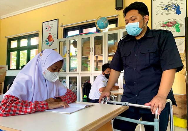 AKTIF MENGAJAR: Reza Pahlevi yang menyandang tunadaksa menjadio guru bahasa Inggris di SMPN 27 Surabaya. (Hanna Septiana/Jawa Pos) - Image