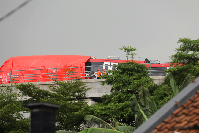Petugas saat melakukan evakuasi pada LRT Cibubur yang tabarkan di ruas rel Munjul Jakarta Timur, Senin, (25/10/2021). Dua kereta LRT dilaporkan tengah dalam tahap uji coba, terlihat 2 badan kereta di tutup terpal oranye saat evakuasi. Foto: Dery Ridwansah - Image