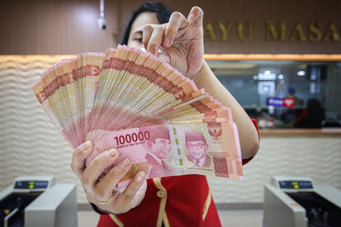Karyawan menghitung uang rupiah di tempat Penukaran uang Ayu Masagung, Jakarta, Kamis (14/10/2021). Nilai tukar rupiah terhadap dolar Amerika Serikat (AS) menguat pada perdagangan pasar spot hari ini, setelah stagnan kemarin. FOTO:MIFTAHULHAYAT/JAWA POS - Image