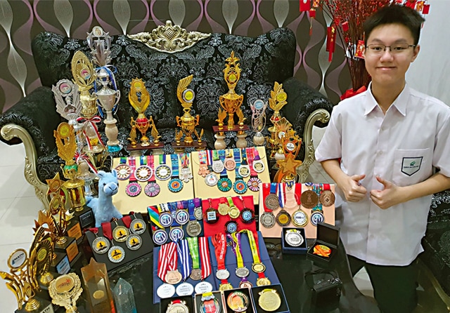 BERPRESTASI: Alvaro Vincent Wijaya dengan deretan piagam dan piala yang dikumpulkan sejak 2018 hingga saat ini. (Alvaro for Jawa Pos) - Image