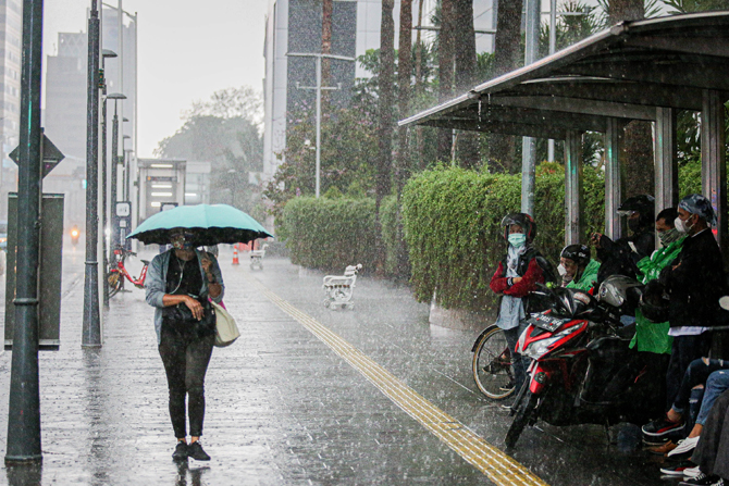Warga melintasi jalan saat hujan di kawasan Jalan MH Thamrin, Jakarta, Senin (1/11/2021). Badan Meteorologi, Klimatologi, dan Geofisika (BMKG) mengeluarkan peringatan dini cuaca ekstrem berupa hujan dengan intensitas sedang hingga lebat yang dapat diserta - Image