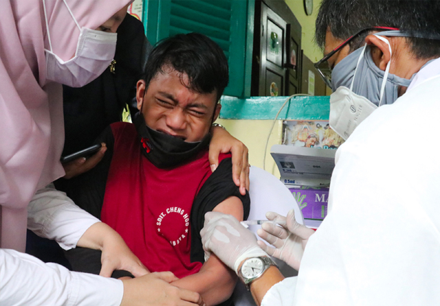 TAHAN YA NAK: Siswa SDIT Cheng Hoo Surabaya, Sangadjue AlGhozali Huda saat mengikuti vaksinasi anak usia 6 hingga 11 tahun di SDN Kaliasin 1 Surabaya, Rabu (15/12) lalu. (Frizal/Jawa Pos) - Image