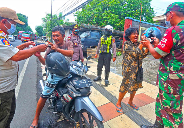 AYO BU, PAKAI MASKER: Petugas gabungan mulai gencar mengingatkan bahaya varian Omicron dan membagikan masker di Jalan Perak Barat, Rabu (9/2). (Ahmad Khusaini/Jawa Pos) - Image