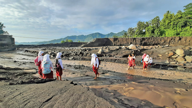 RUTE BERISIKO: Anak-anak menyeberangi Kali Regoyo yang memisahkan Dusun Sumberlangsep dengan Sumber Kajar, Desa Jugosari, Lumajang, kemarin. (EDI SUSILO/JAWA POS) - Image