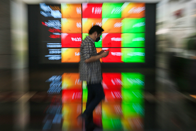 Karyawan melintas didekat monitor pergerakan harga saham Bursa Efek Indonesia, Jakarta, Rabu (6/4/2022). Nilai kapitalisasi pasar (market cap) Bursa Efek Indonesia (BEI) menembus Rp 9.000 triliun, tepatnya Rp 9.006 triliun, pada perdagangan Selasa (5/4/20 - Image
