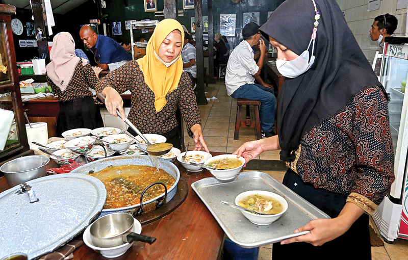 JAM SIBUK: Pelanggan Soto Gading lebih suka menyantap langsung hidangan mereka di warung. Baik saat sarapan maupun jeda antarjam makan. (RIANA SETIAWAN/JAWA POS) - Image