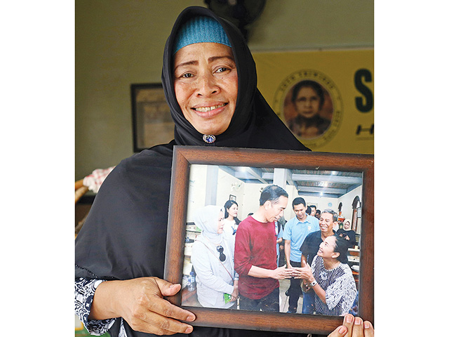 GENERASI KETIGA: Sri Suwati memperlihatkan foto Presiden Jokowi saat mampir ke Soto Triwindu. (RIANA SETIAWAN/JAWA POS) - Image
