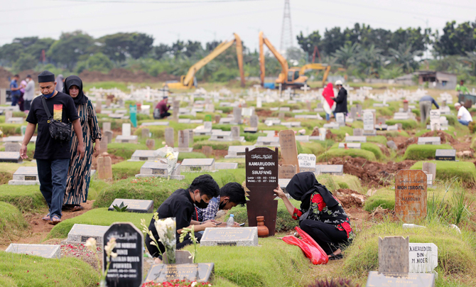 Warga berdoa di sisi makam keluarganya saat berziarah di Tempat Pemakaman Umum (TPU) Covid 19 Rorotan, Jakarta, Selasa (3/5/2022). Pada hari kedua Lebaran, TPU tersebut ramai peziarah untuk mendoakan sanak keluarga dan kerabat yang sudah wafat. FOTO : FED - Image