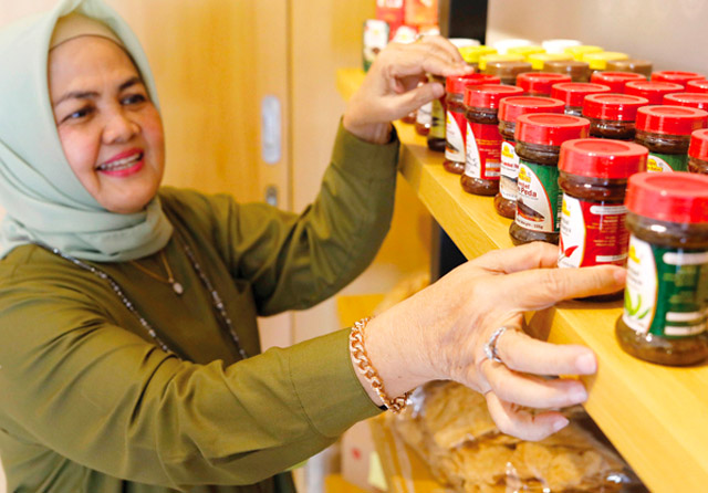 BERTAHAN LEBIH DARI SATU DEKADE: Susilaningsih menata beberapa produk di workshop-nya di kawasan Tenggilis, Surabaya. Dia telah memproduksi dan mengolah sambal selama 11 tahun. (Puguh Sujiatmiko/Jawa Pos) - Image