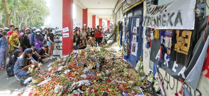 MENGALIR TERUS: Sejumlah warga mendoakan korban tragedi Kanjuruhan di gate 13 Stadion Kanjuruhan, Kabupaten Malang, kemarin (9/10). (ROBERTUS RISKY/JAWA POS) - Image