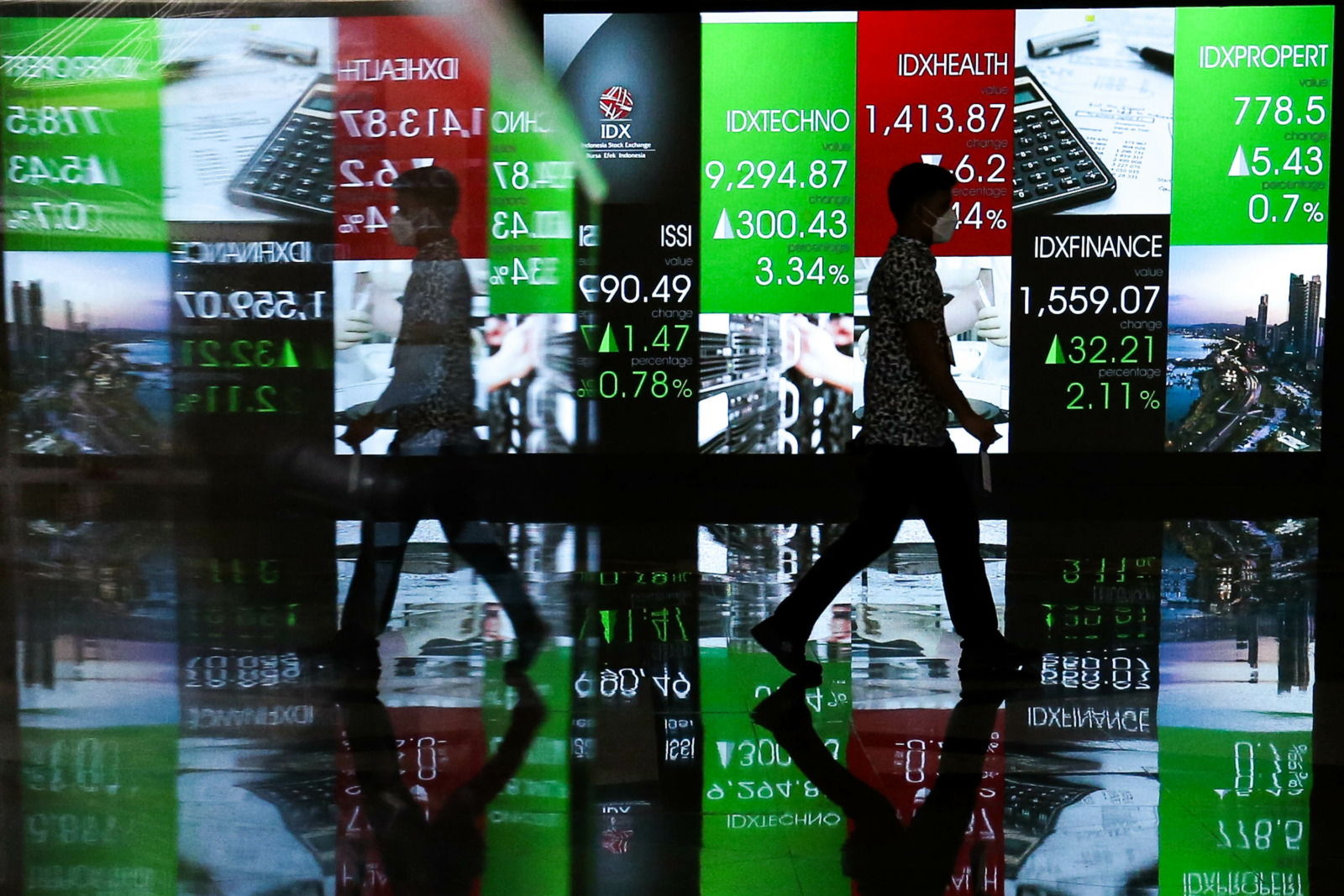 Karyawan melintas didekat latar layar pergerakan indeks harga saham gabungan (IHSG) di gedung Bursa Efek Indonesia (BEI), Jakarta, Senin (3/1/2022). Pembukaan perdagangan Bursa Efek Indonesia pada 2022 dilakukan oleh Presiden Joko Widodo. IHSG ditutup nai - Image