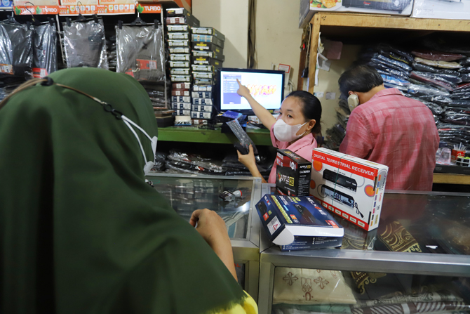 Pedagang melayani pembeli set top box (STB) TV Digital di pusat elektronik Pasar Kebayoran Lama, Jakarta, Jumat (4/2/2022). Hari pertama migrasi tv analog ke tv digital membuat penjualan STB meningkat pesat. Bahkan sudah sejak 2 minggu sebelum migrasi s - Image
