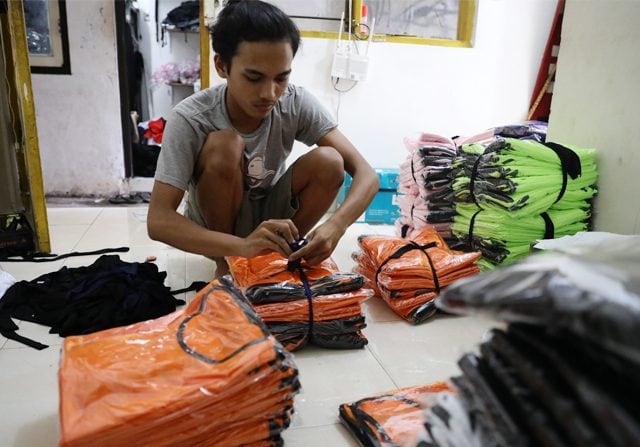 Ilustrasi pekerja UMKM saat merapihkan baju yang hendeka di paking untuk di kirim sentra tekstil baju di kawasan Ciputat (Dery Ridwansah/JawaPos.com). - Image