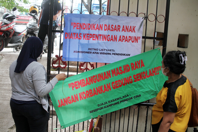 Orang tua siswa membubuhkan pernyataan penolakan diatas kain di SDN 01, Pondok Cina, Depok, Minggu (11/12/2022). Siswa SDN Pondok Cina 1 melaksanakan ujian Penilaian Akhir Semester (PAS) di sekolahnya hingga 9 Desember 2022 sebelum sekolah tersebut direlo - Image