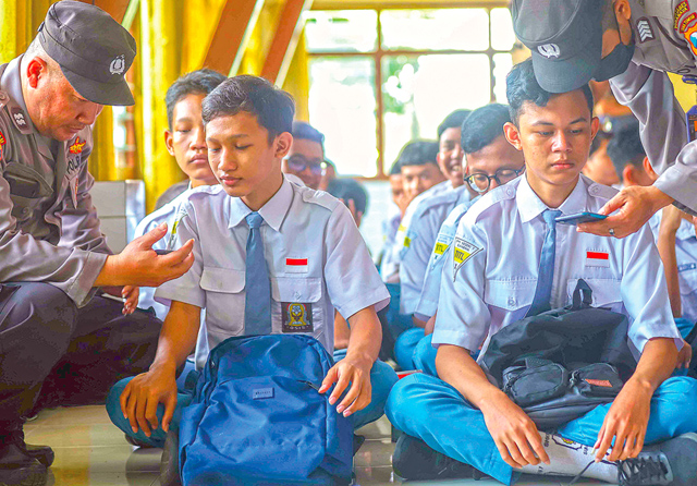CEK DULU HANDPHONENYA: Sejumlah polisi dari Polrestabes Surabaya dan Polsek Bubutan memeriksa ponsel siswa kelas X dan XII SMKN 7 Surabaya (6/12) untuk melacak anggota geng. Dalam pengecekan itu, polisi tidak menemukan tandatanda siswa bergabung dengan g - Image