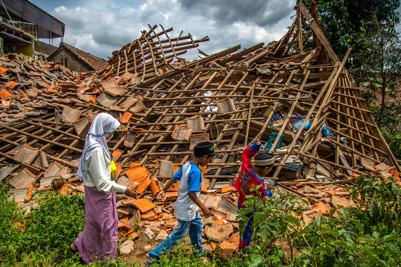 BERMAIN: Anak-anak korban gempa berjalan melewati rumah yang roboh di Desa Cugenang, Cianjur, Jawa Barat, kemarin (1/12). (AFP) - Image