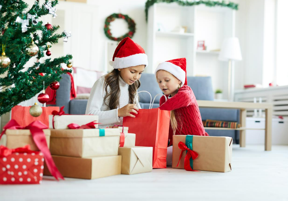 Ilustrasi dua anak yang sedang membuka kado Natal