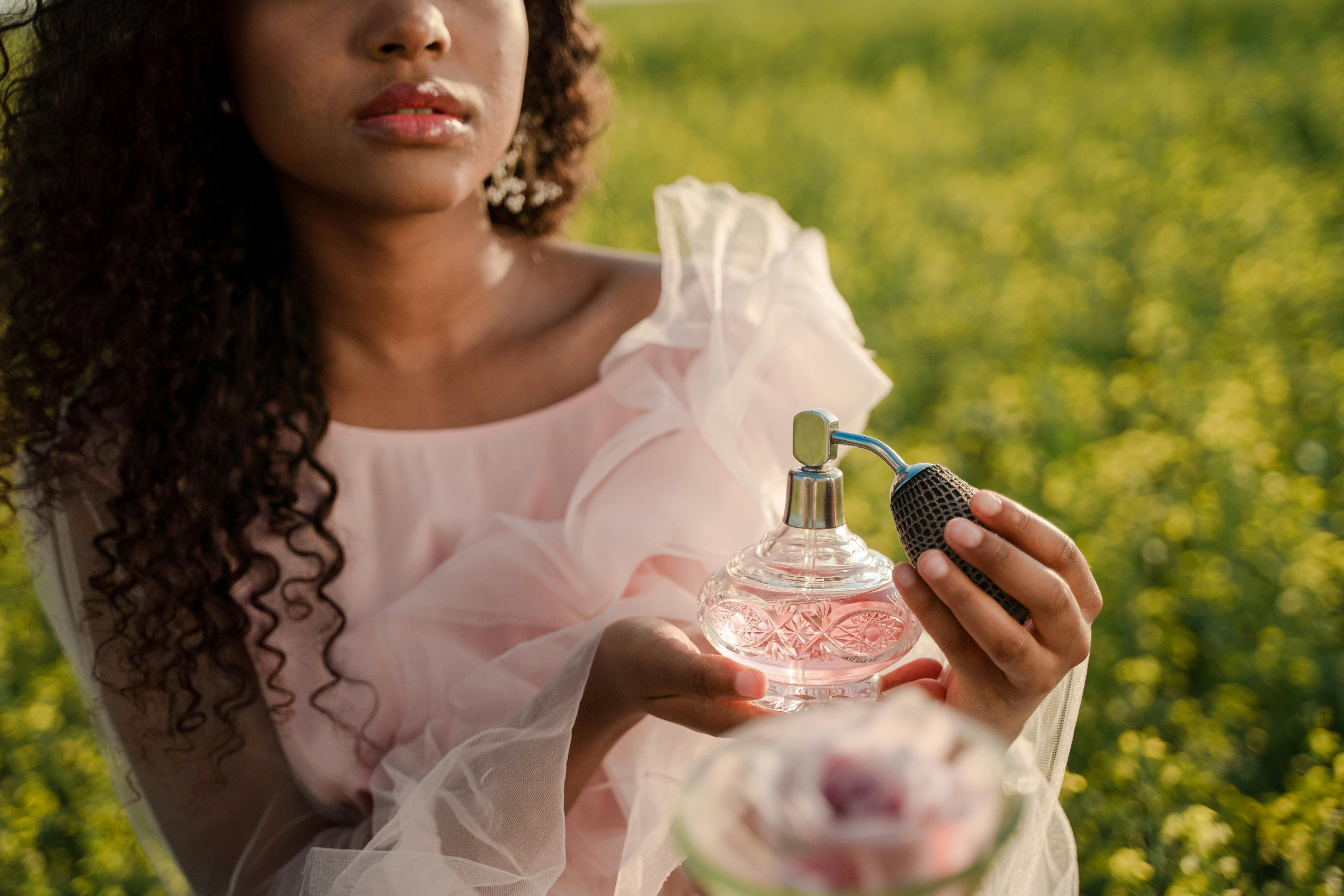 Ilustrasi seseorang menyemprotkan parfum di padang rumput