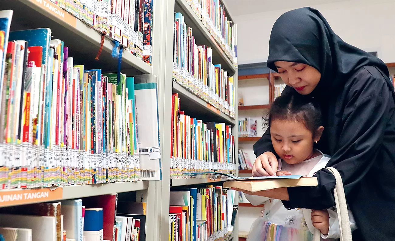 Ilustrasi anak dan orangtua membaca di perpustakaan.