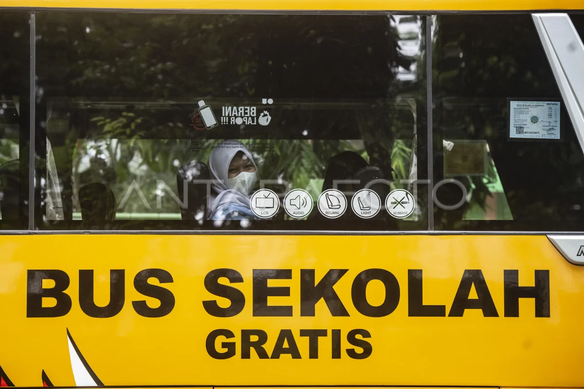 Seorang siswi yang sedang duduk di dalam bus sekolah gratis.