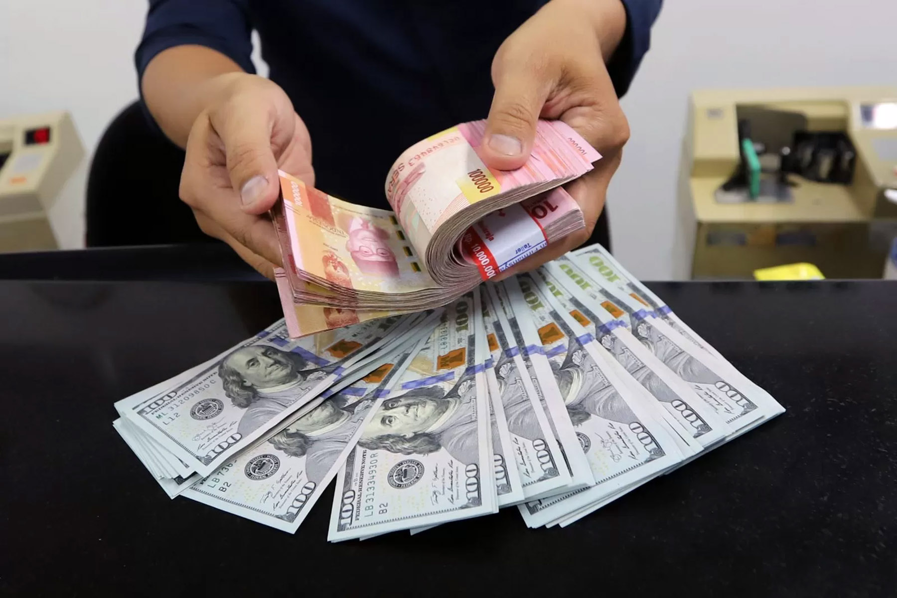 Petugas menghitung rupiah dan dollar di sebuah money changer. (Dery Ridwansah/JawaPos.com)
