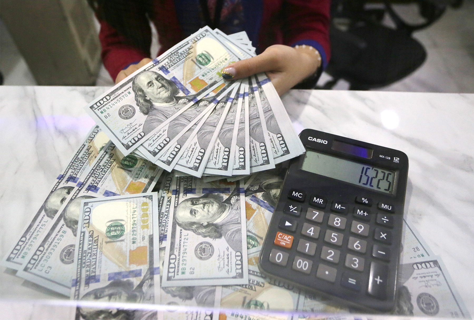 Petugas menghitung pecahan 100 dolar AS di jasa penukaran uang asing Dolar Indo, Melawai, Jakarta.