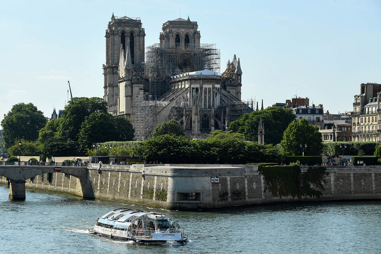 Sebuah perahu melintas di Sungai Seine dengan latar belakang Katedral Notre-Dame de Paris yang mendapatkan renovasi besar-besaran setelah kebakaran dahsyat pada April 2019. (Foto: Bertrand Guay / AFP)