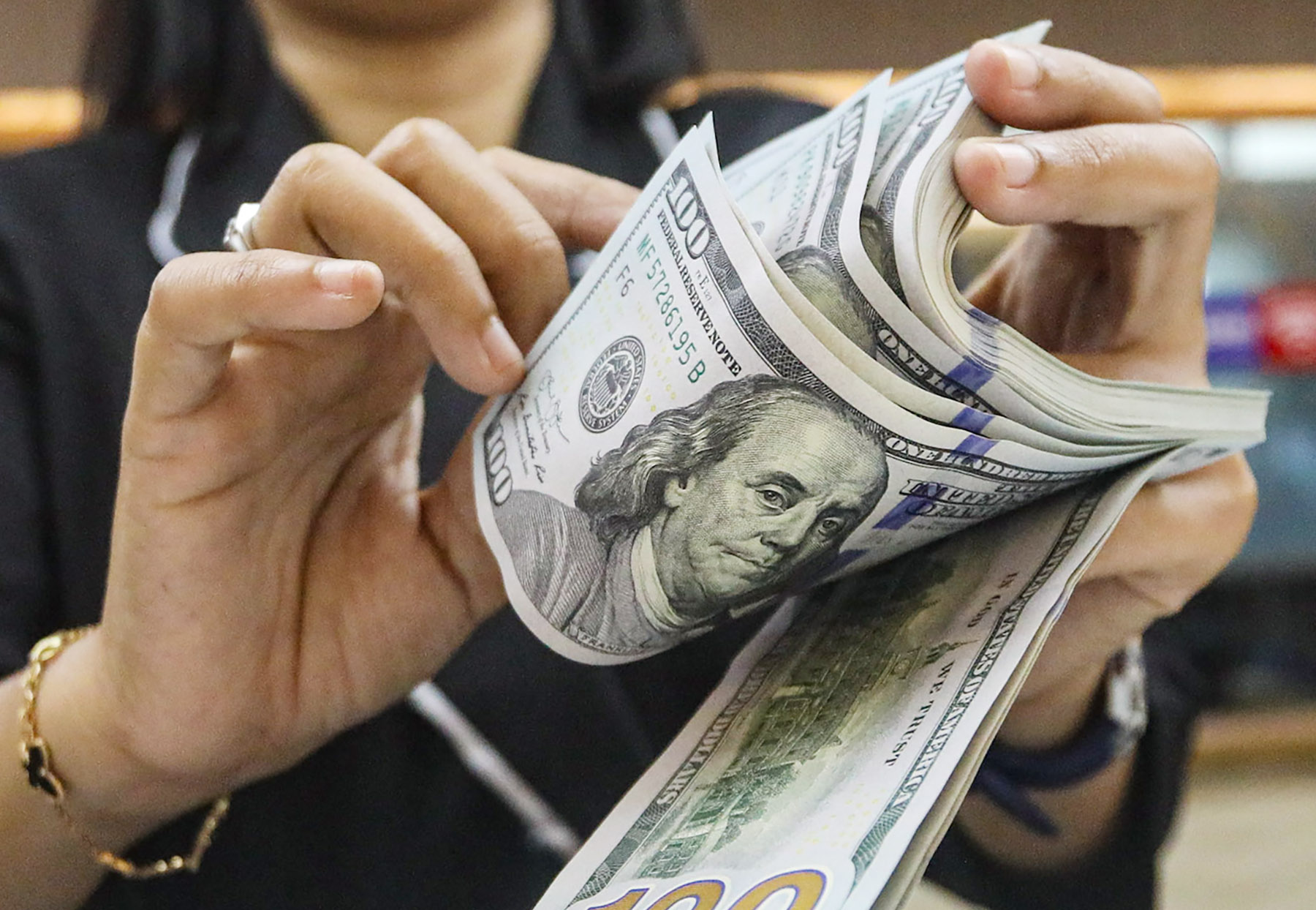 Petugas menghitung Dolar AS di gerai penukaran mata uang asing Ayu Masagung di Jakarta, Senin (15/12/2024).