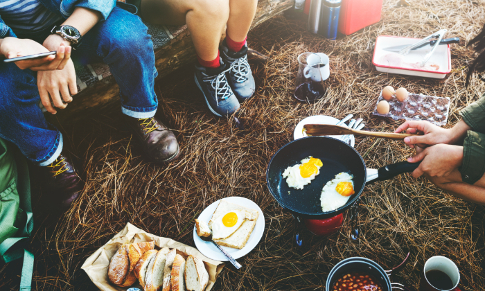 Ilustrasi sekelompok teman yang sedang memasak bahan makanan saat camping.