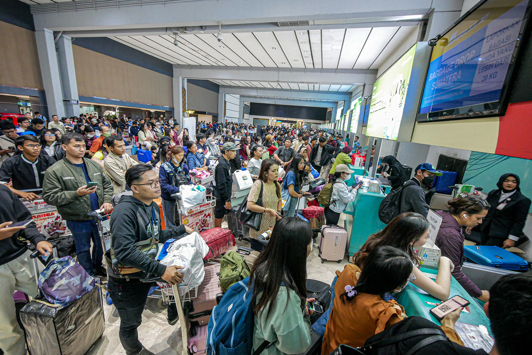 Sejumlah penumpang pesawat mengantri di counter check-in di Terminal 2, Bandara Soekarno-Hatta, Sabtu (21/12/2024).
