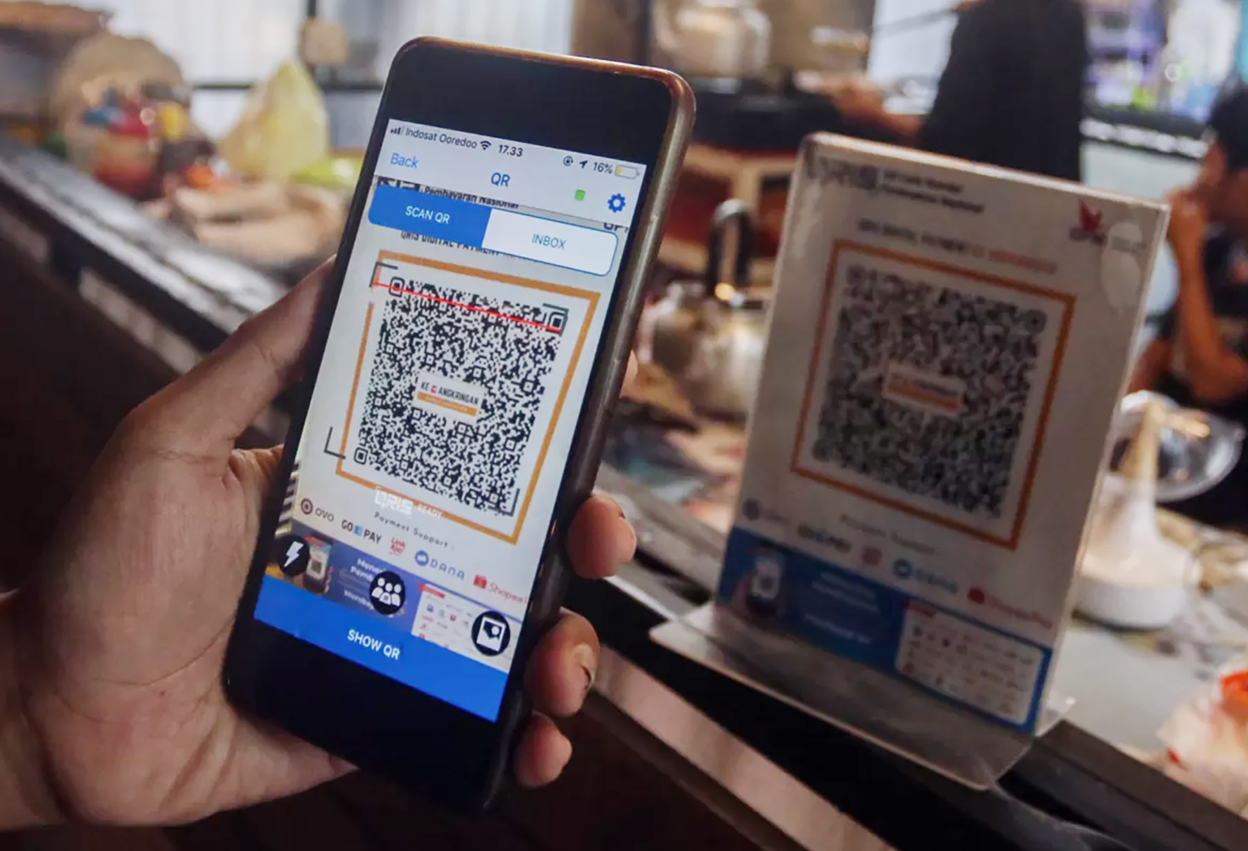 Seorang pelanggan memindai kode batang Quick Response Code Indonesian Standard (QRIS) dengan gawainya saat transaksi melalui aplikasi digital perbankan di kedai Pewarta Foto Indonesia (PFI), Jakarta.