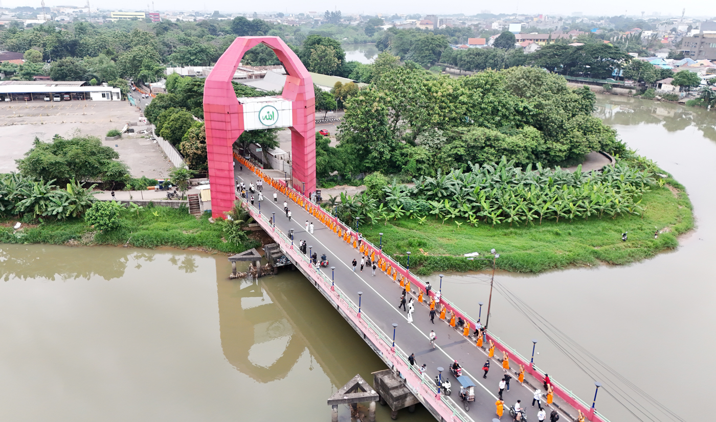 Foto udara Biksu Thudong bersama peserta Samanera berjalan melintasi Jembatan Merah dalam rangkaian Pabajja Samanera di Kota Tangerang, Banten, Minggu (29/12/2024).  (Dery Ridwansah/ JawaPos.com)
