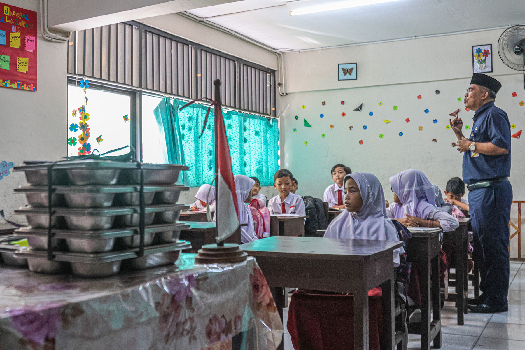 Sejumlah guru membagikan tray makanan MBG ke siswa kelas 3 saat program Makan Bergizi Gratis (MBG) d