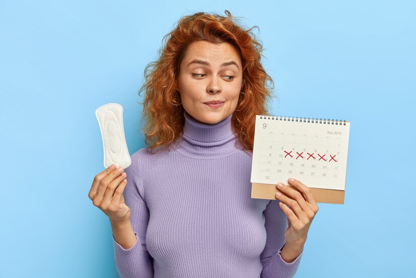 Ilustrasi wanita muda memperlihatkan kalender menstruasi