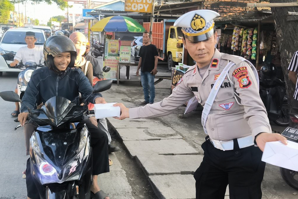 Petugas saat memberikan takjil kepada pengendara sepeda motor. (Polda Metro Jaya)