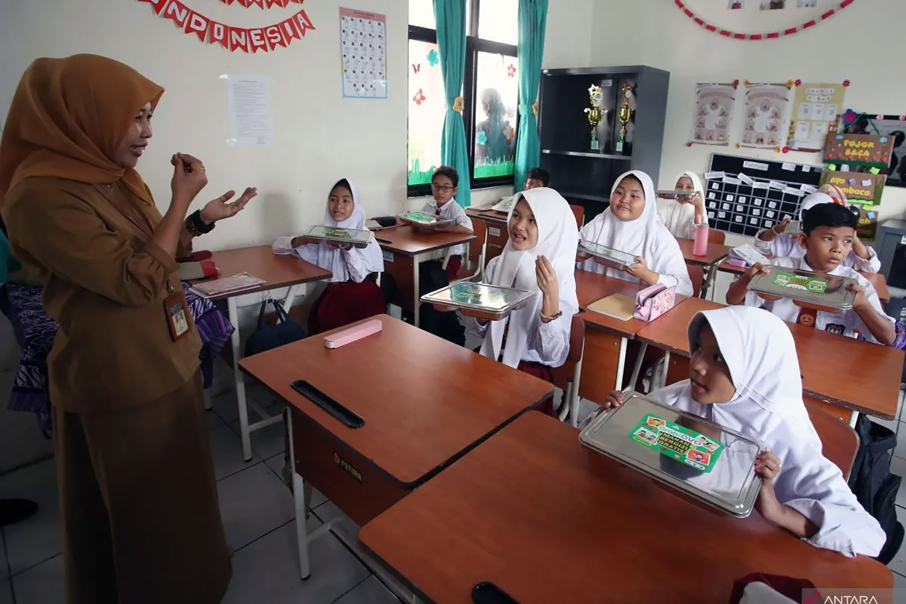 Seorang guru mengarahkan murid berkebutuhan khusus sebelum menyantap makanan saat pelaksanaan makanan bergizi gratis (MBG) di Sekolah Khusus Negeri 01 Tangsel, Pondok Kacang, Tangerang Selatan, Banten