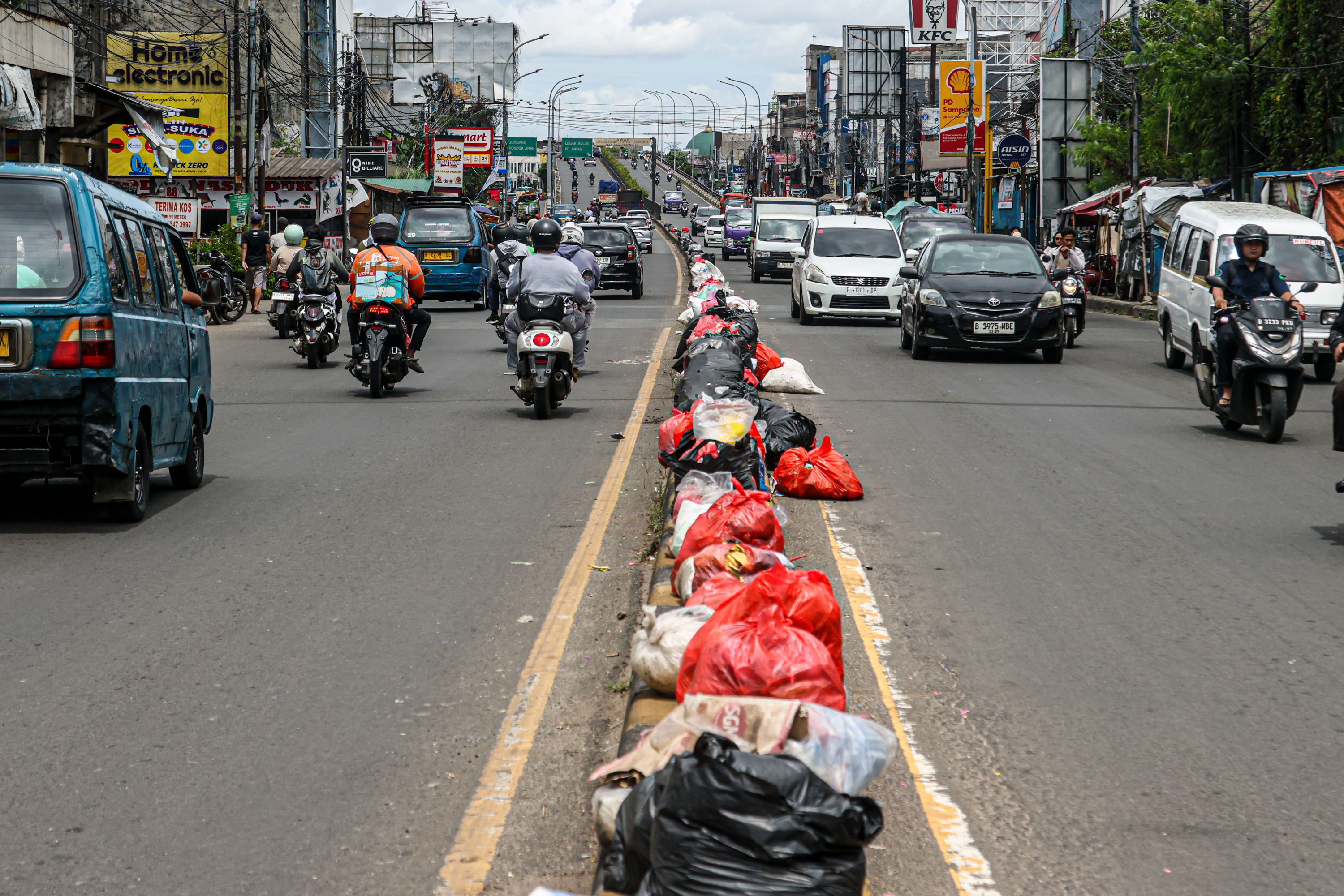 Aktifitas warga di sekitar tumpukan sampah di Jalan Dewi Sartika, Ciputat, Tangerang Selatan, Selasa (16/12/2025). Sampah yang menumpuk di pinggir jalan tersebut disebabkan adanya penataan gunungan sampah di Tempat Pembuangan Akhir (TPA) Cipeucang sehingg